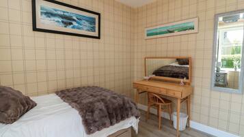 Un dormitorio con cama, un escritorio y dos cuadros en la pared.