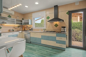 A kitchen with a dining table, cabinets, and a window. - Cal Piano Vacation Home with Private Pool, Wi-Fi, and Air Conditioning (Palol de Revardit)