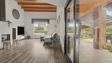 A spacious living room with a wooden ceiling, a large window, and a view of the outdoors.