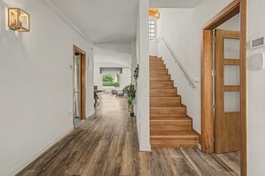 A wooden staircase leading to a landing with a view of a garden, a hallway with a light fixture, and a door with a window.
