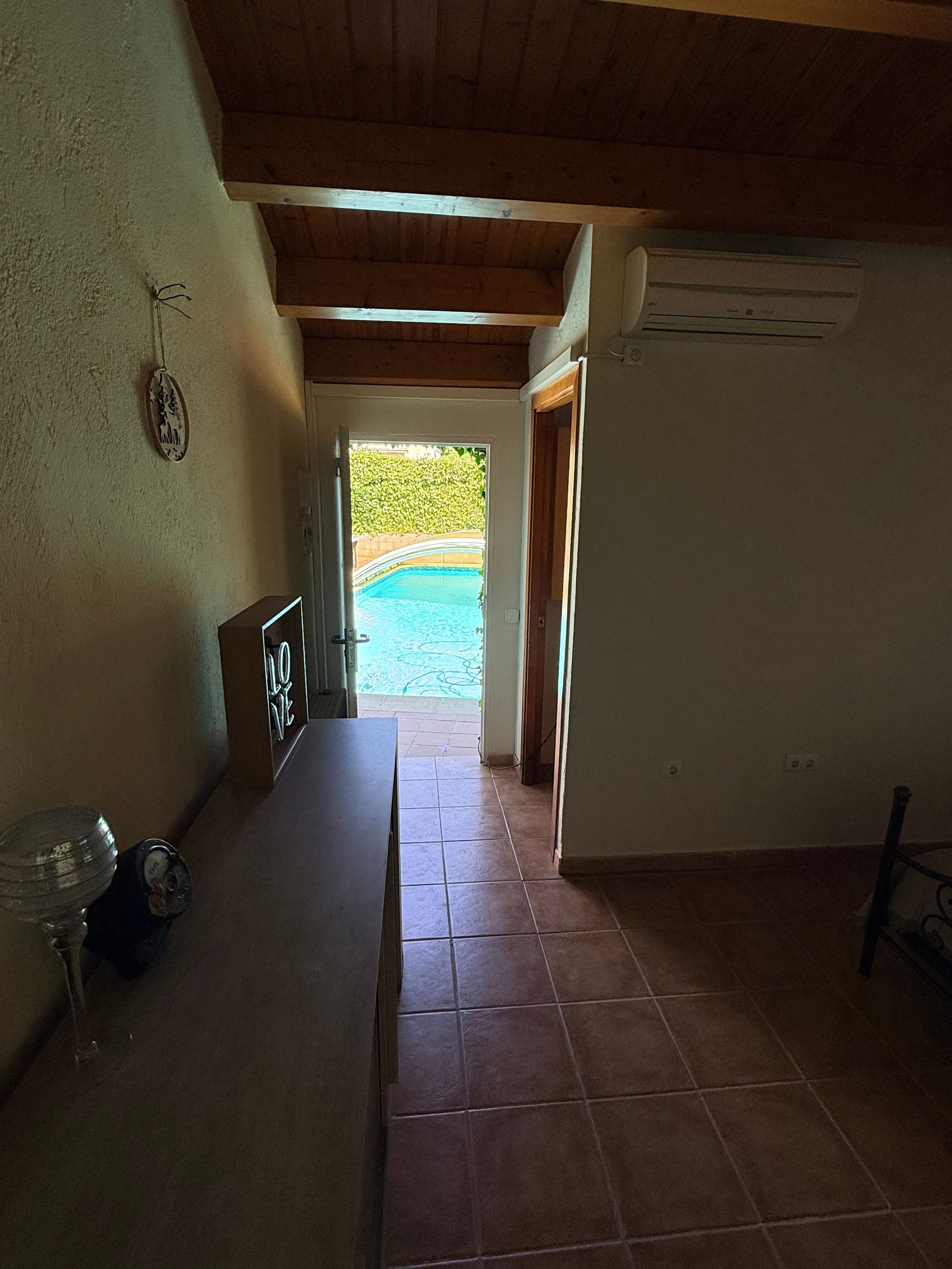 Ein Zimmer mit Blick auf ein Schwimmbecken durch einen offenen Durchgang.