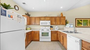 A kitchen with wooden cabinets, a white refrigerator, a microwave, a stove, and a dishwasher. - 933 Willow Bend - Barefoot Resort Rentals (North Myrtle Beach)