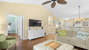 A living room with a television, a sofa, a coffee table, and a ceiling fan. - 933 Willow Bend - Barefoot Resort Rentals (North Myrtle Beach)