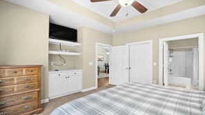 Ein Schlafzimmer mit Bett, Kommode, Fernseher, Kleiderschrank und Deckenventilator.