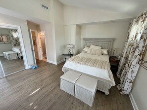 A bedroom with a large bed, a bedside table, a lamp, a bench, and a mirror. - 3 bedroom 2.5 bath Townhome just a few short blocks to the beach. (Wildwood Crest)