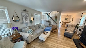 A spacious living area with a sofa, ottoman, and chairs, a staircase, and a dining area with a table and chairs. - 3 bedroom 2.5 bath Townhome just a few short blocks to the beach. (Wildwood Crest)