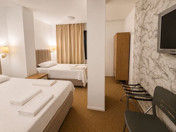 A hotel room with two beds, a wardrobe, a television, and a chair. - çayır otel (Marmara Ereglisi)