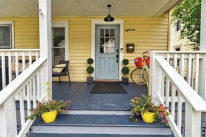 A porch with a blue door, a bicycle, and two potted plants.