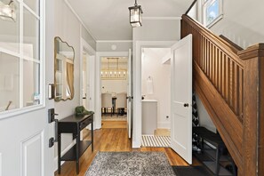A hallway with a wooden staircase, a mirror, a desk, and a chandelier. - Near Wineries | Sleeps 9 | Walking distance to Geneva (Geneva)