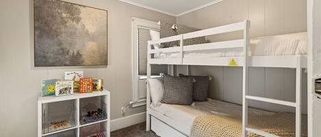 A child's bedroom with bunk beds, a bookshelf, and a large abstract painting.