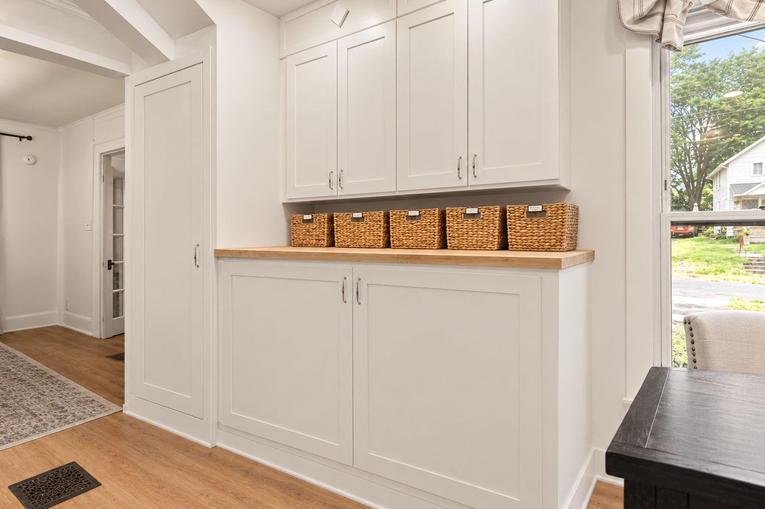 A kitchen with white cabinets, a wooden countertop, and wicker baskets.