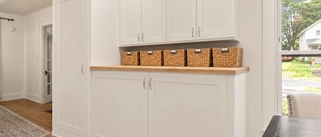 A kitchen with white cabinets, a wooden countertop, and wicker baskets.