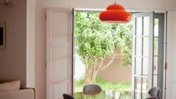 A room with a dining table and chairs, a door leading outside, and a hanging light fixture. - 132 Beach House | Vacation Home in Zambujeira do Mar (Zambujeira do Mar)