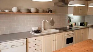 A modern kitchen with white cabinets, a wooden countertop, and pendant lighting. - 132 Beach House | Vacation Home in Zambujeira do Mar (Zambujeira do Mar)