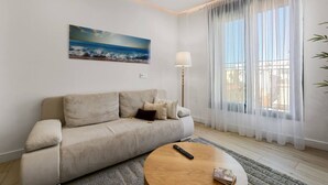 A living room with a sofa, a round coffee table, a lamp, and a painting on the wall. - Old Town Estepona Penthouse (Estepona)