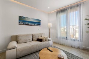 A living room with a sofa, a round coffee table, a lamp, and a painting on the wall. - Old Town Estepona Penthouse (Estepona)