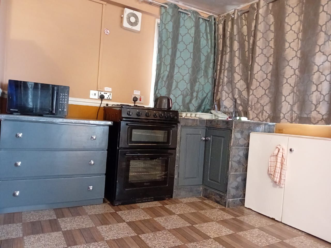 A compact kitchen with a stove, oven, and a blue cabinet.