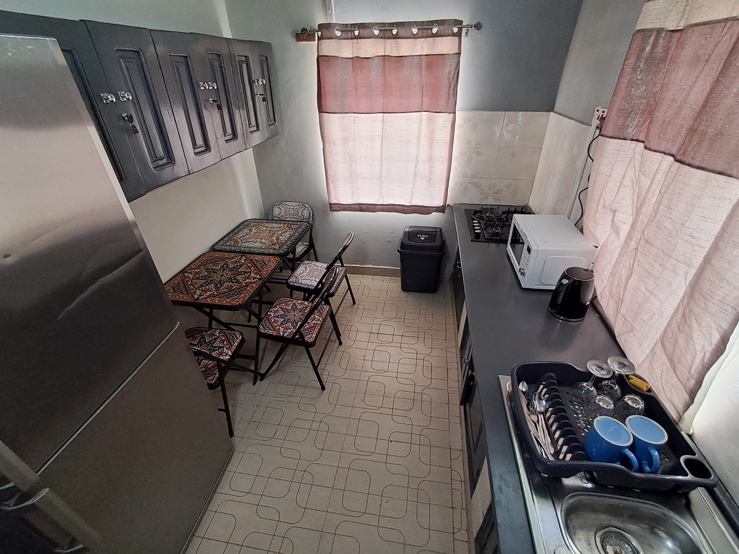 Une cuisine compacte comprenant une table à manger, des chaises, une cuisinière, un four à micro-ondes et un évier.