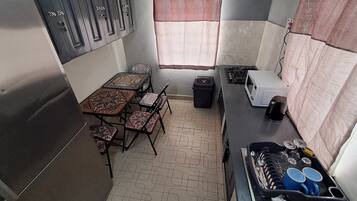 Une cuisine compacte comprenant une table à manger, des chaises, une cuisinière, un four à micro-ondes et un évier.
