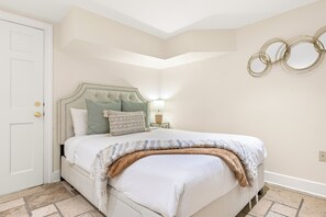 Ein Schlafzimmer mit einem Bett, einem Nachttisch, einer Lampe und einer Tür.