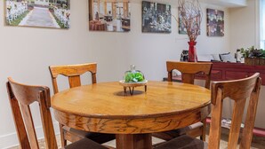 A round wooden dining table with six chairs, surrounded by framed photographs on the wall. - Best Location Near Madison Square, Walk Everywhere by Lucky Savannah (Savannah)