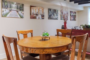 Ein runder Holztisch mit sechs Stühlen, umgeben von gerahmten Fotos an der Wand.