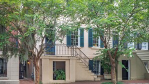 A two-story building with a beige facade, blue shutters, and a visible number '19' on the window. - Best Location Near Madison Square, Walk Everywhere by Lucky Savannah (Savannah)