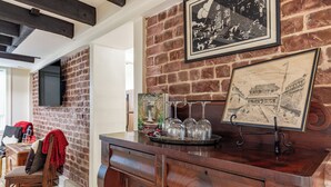 A bar area with a wooden counter, a map, and a television mounted on a brick wall. - Best Location Near Madison Square, Walk Everywhere by Lucky Savannah (Savannah)