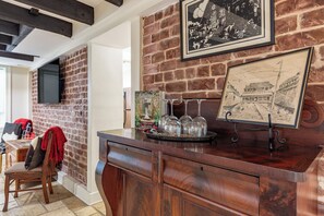 Eine Bar mit einer Holztresen, einer Karte und einem an einer Ziegelwand befestigten Fernseher.