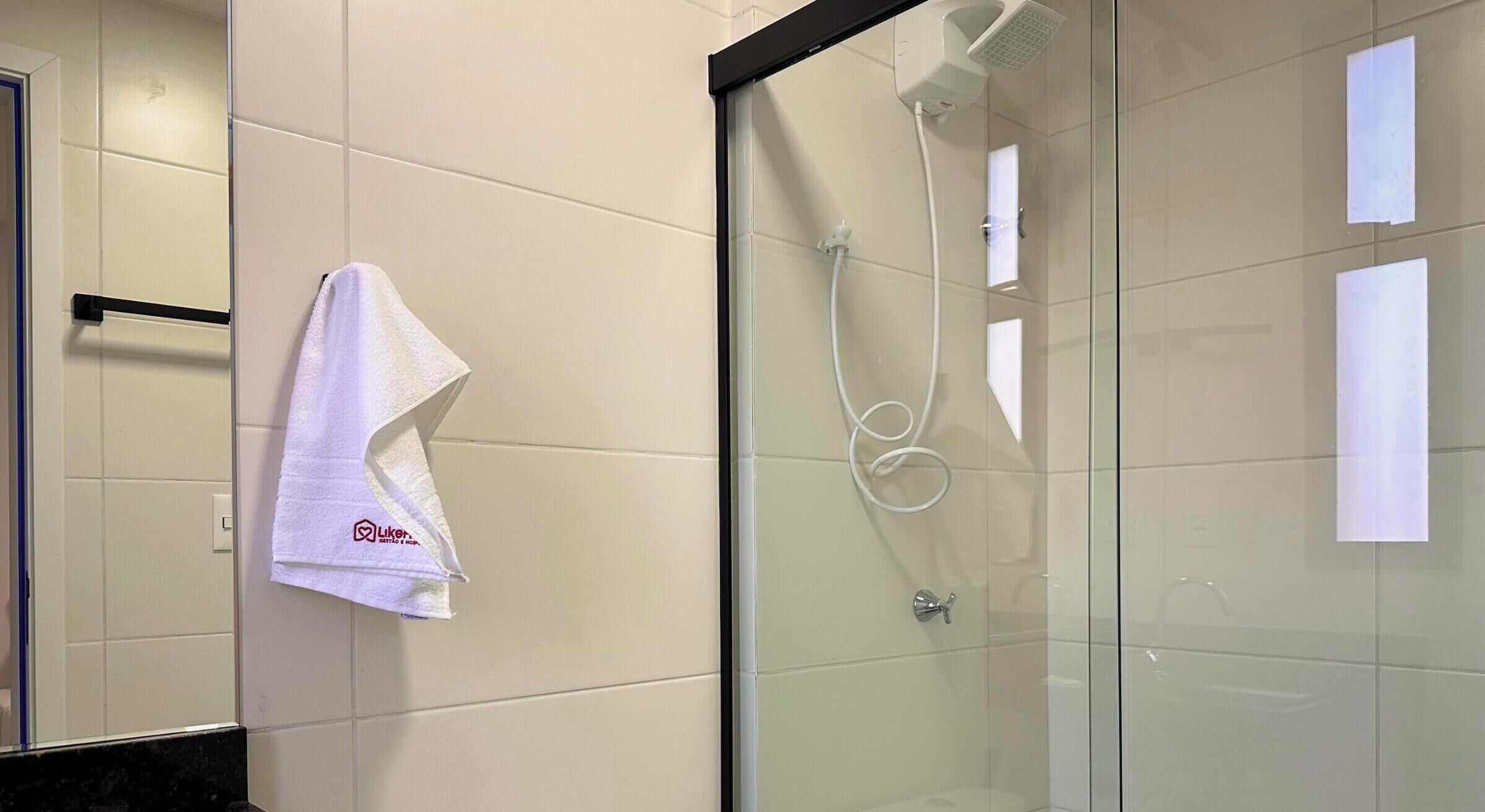 A bathroom with a glass shower enclosure, a towel hanging on a rack, and a visible shower head.