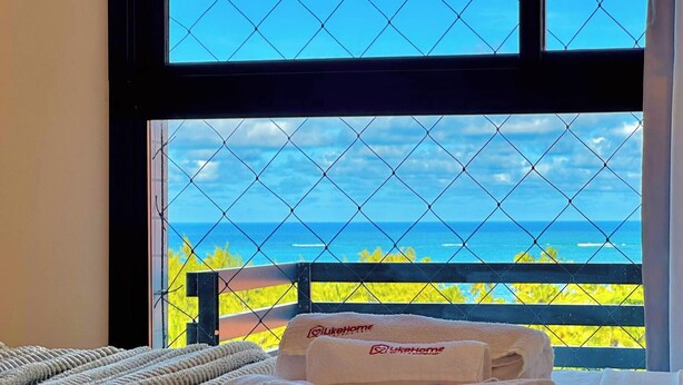 Een kamer met een bed, een raam met uitzicht op de oceaan en een handdoek met een logo.