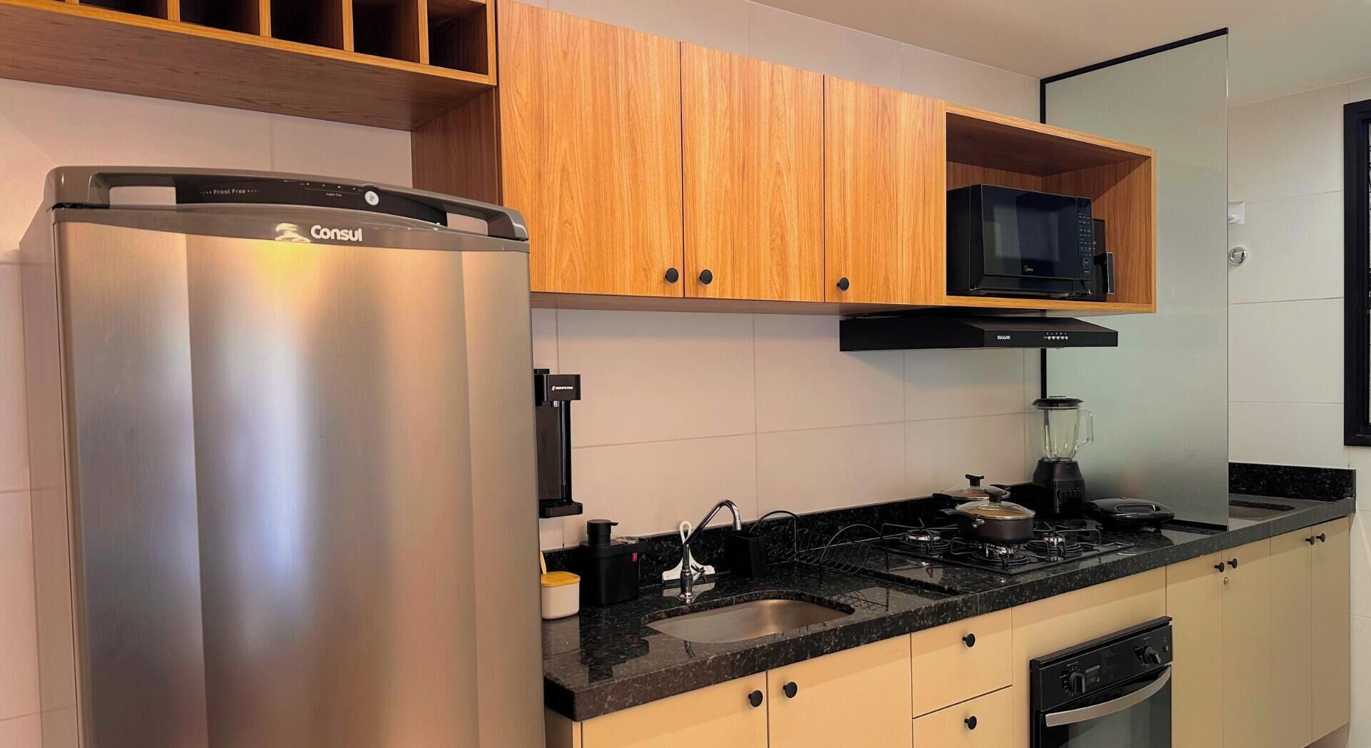 A modern kitchen with stainless steel appliances, wooden cabinets, and a black countertop.