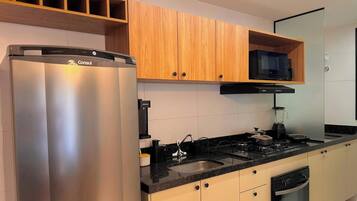 A modern kitchen with stainless steel appliances, wooden cabinets, and a black countertop.