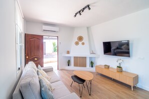Ein modernes Wohnzimmer mit einer Couch, einem Esstisch, einem Fernseher und einem Kamin.