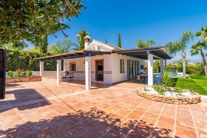Ein überdachter Patio-Bereich mit Pool, Sitzgelegenheiten im Freien und Blick auf die umliegende Landschaft.