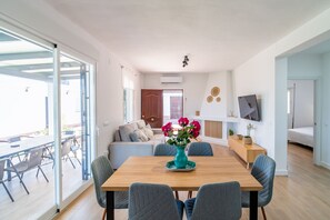 A modern living room with a wooden dining table, grey upholstered chairs, a sofa, and a TV mounted on the wall. - Cubo's Miralmonte Rural House / Private pool / Air conditioning / BBQ (Coín)