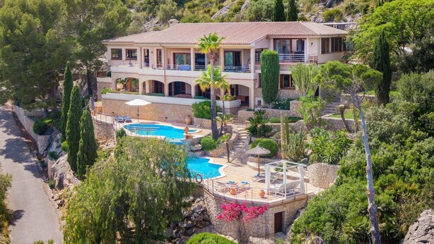 A two-story house with a swimming pool, surrounded by greenery and rocky terrain. - 5-bed Villa, Two Pools, Puerto Pollenca (Pollença)