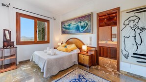 A bedroom with a bed, bedside table, nightstand, and a large window. - 5-bed Villa, Two Pools, Puerto Pollenca (Pollença)