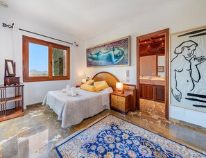 Ein Schlafzimmer mit einem Bett, Nachttisch und einem großen Fenster.