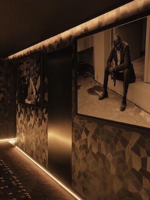 A corridor with patterned walls and a person sitting on a ledge.