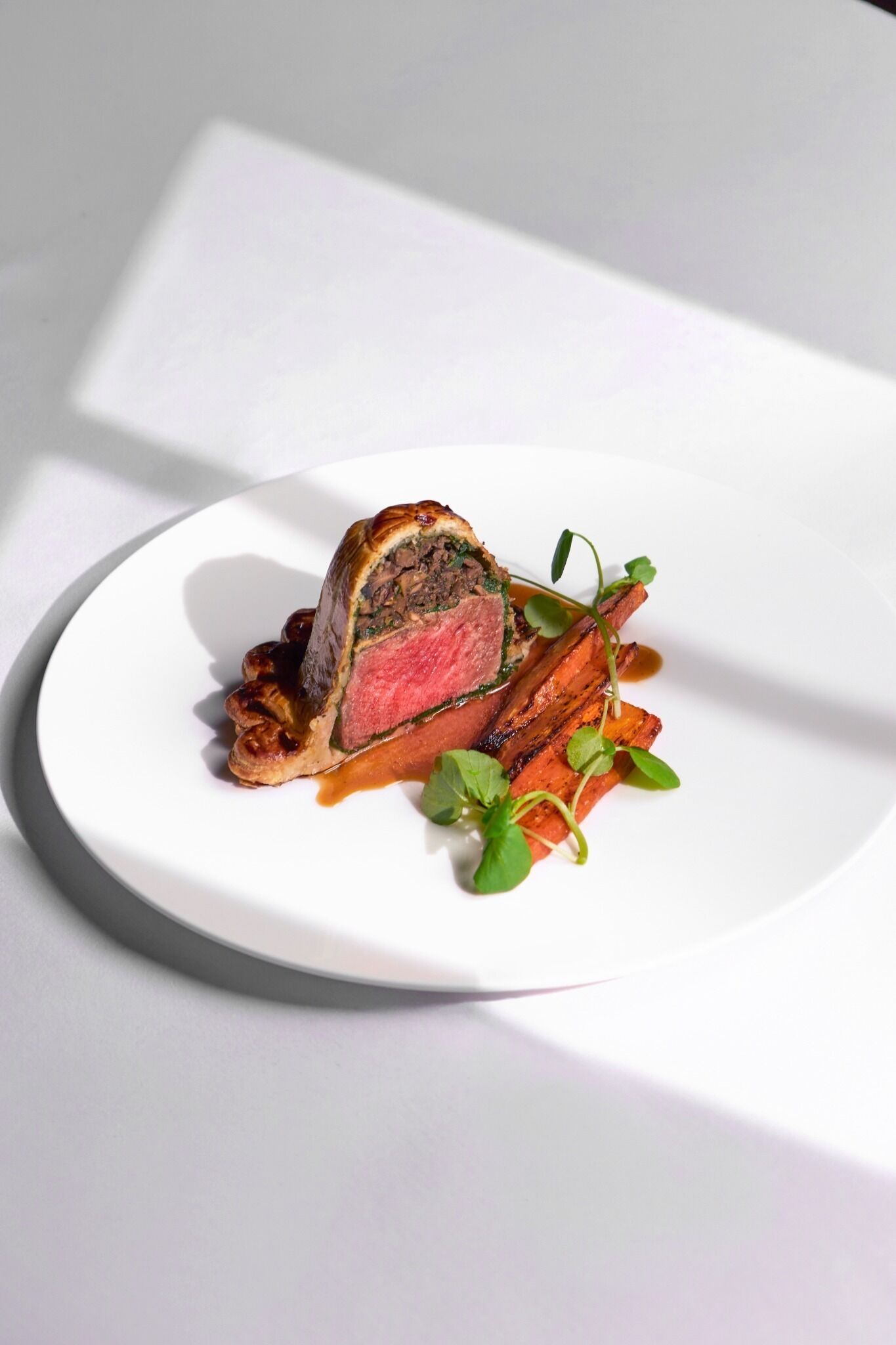 A single slice of meat with a crust on a white plate.