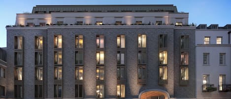 Un hotel a più piani con facciata in mattoni, ampie finestre e un'area caffè/lounge al piano terra.