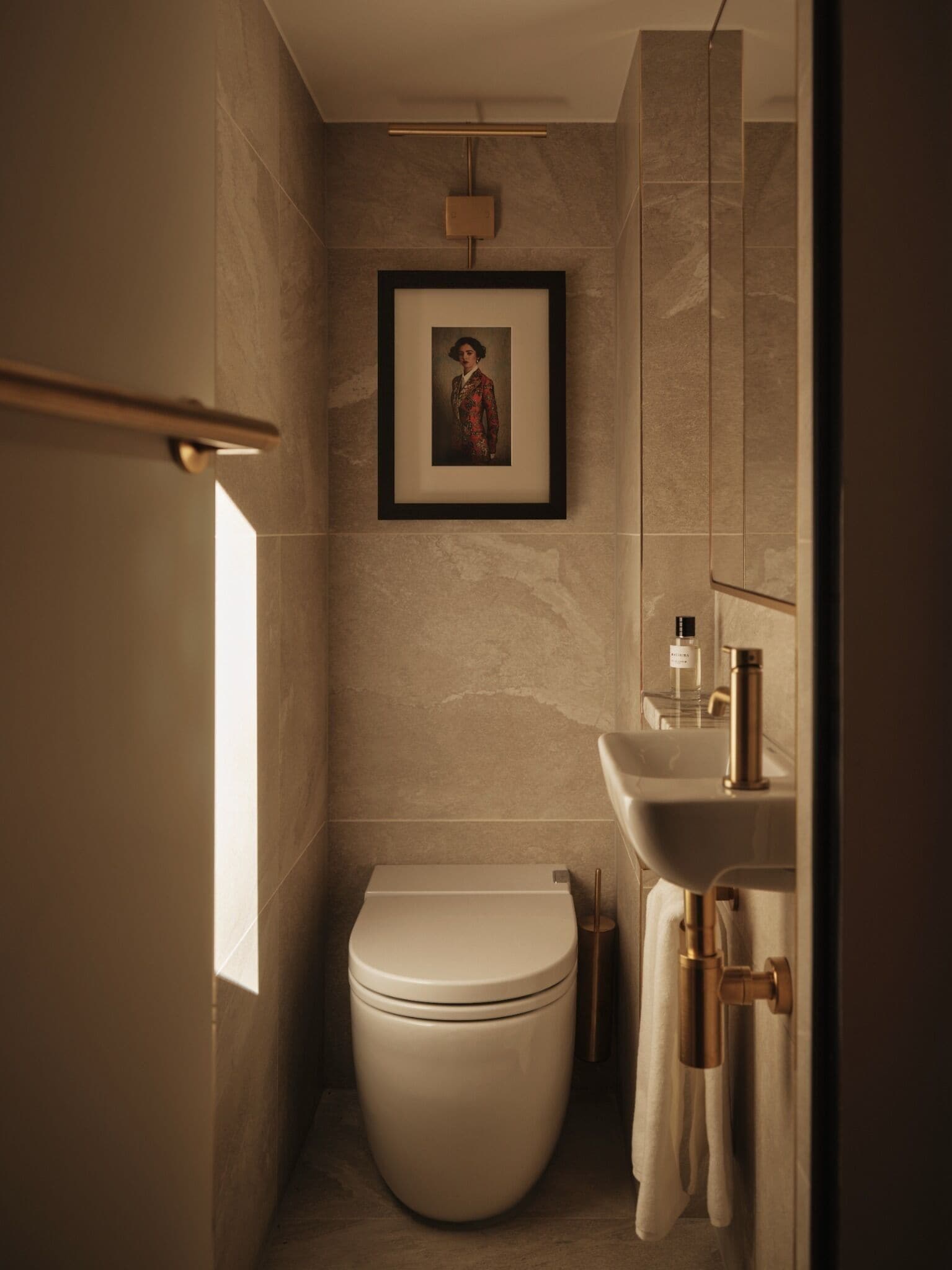 A modern bathroom with a toilet, a framed picture on the wall, and a sink with a mirror.