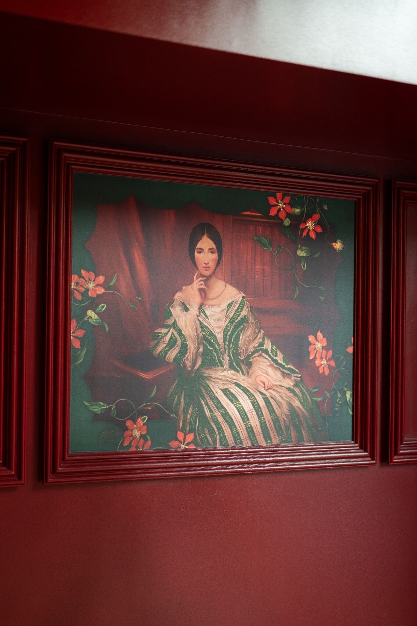 A framed portrait of a person in traditional attire, set against a dark background with floral patterns.