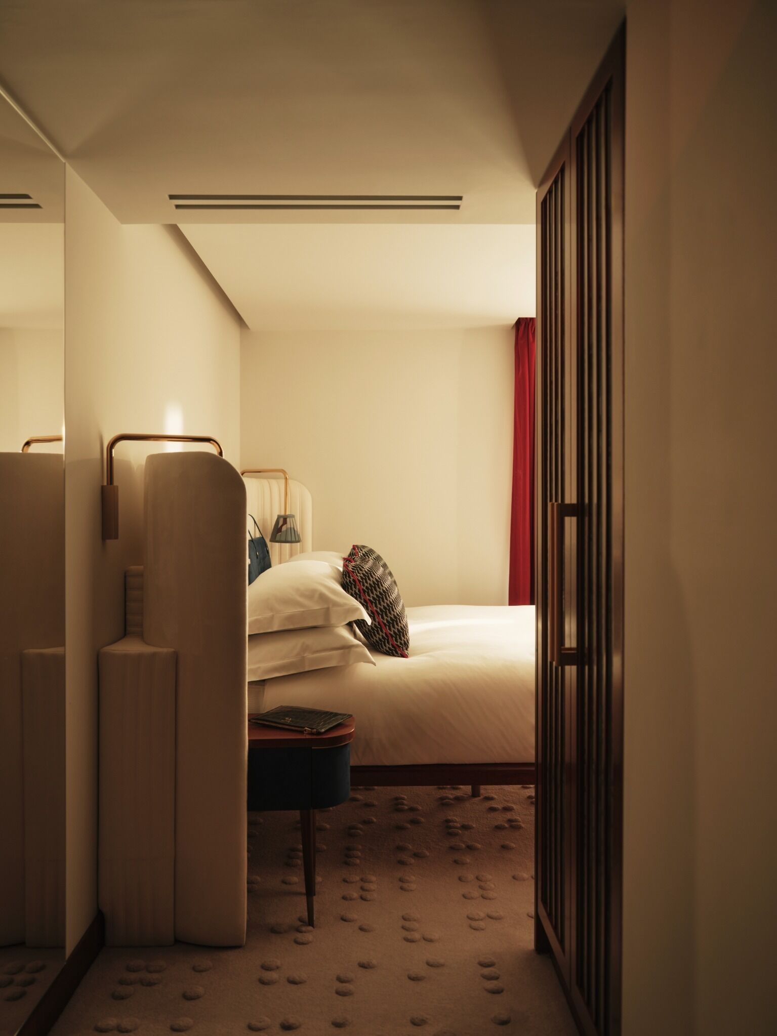 Una habitación de hotel con cama, mesita de noche, lámpara y armario.