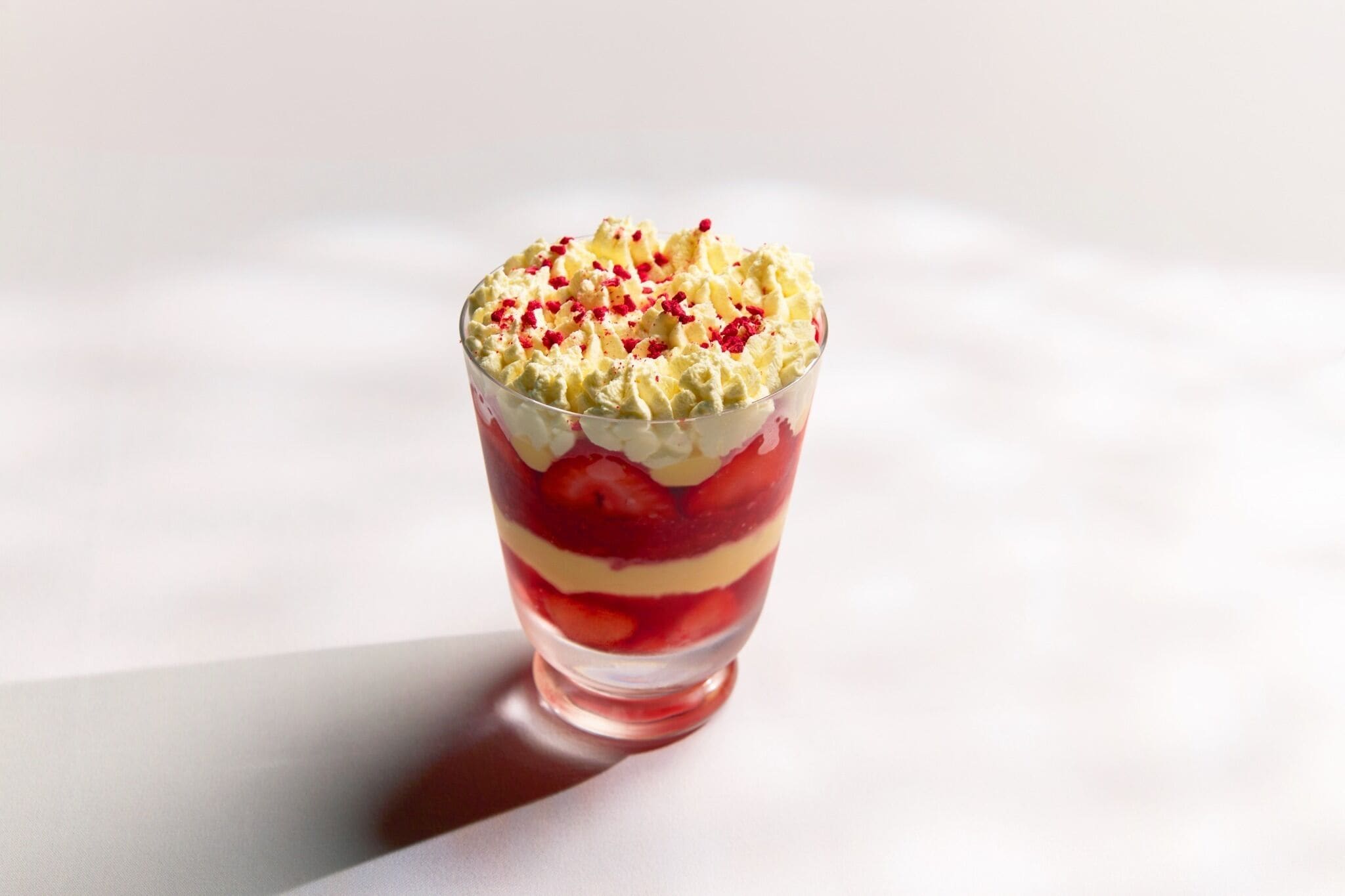 Un dessert composé de plusieurs couches, présenté dans un verre transparent.
