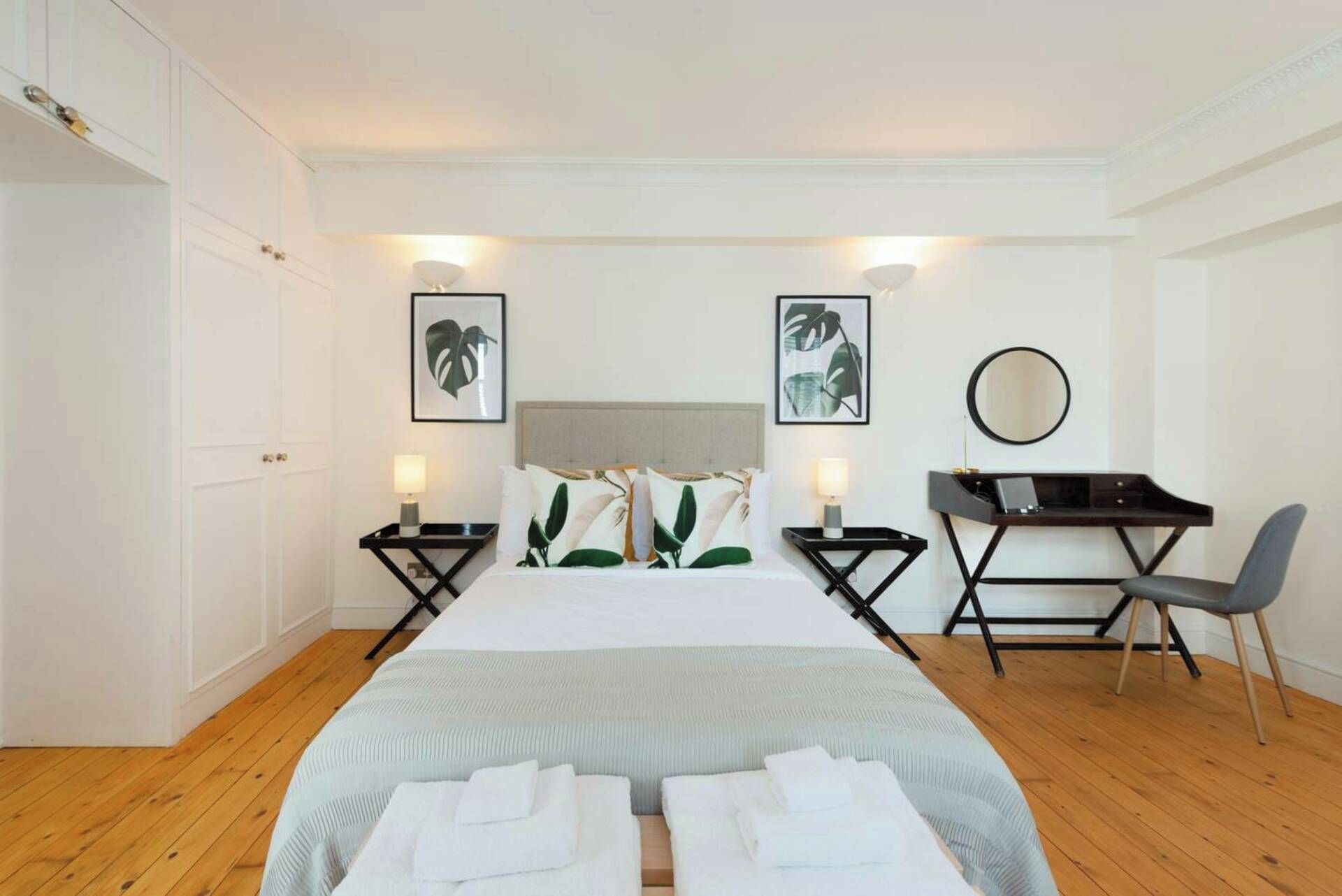 Ein Hotelzimmer mit einem Bett, zwei Nachttischen, einem Schreibtisch mit Stuhl und einem Spiegel.