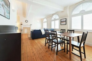 A dining area with a wooden table and chairs, a blue sofa, and a fireplace. - Beautiful 3BDR next to Trafalgar Square - 30+ Days (London)