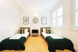 A room with two beds, a mirror, and framed artwork on the walls. - Beautiful 3BDR next to Trafalgar Square - 30+ Days (London)