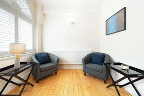 A room with two armchairs, a table, a lamp, and a radiator. - Beautiful 3BDR next to Trafalgar Square - 30+ Days (London)
